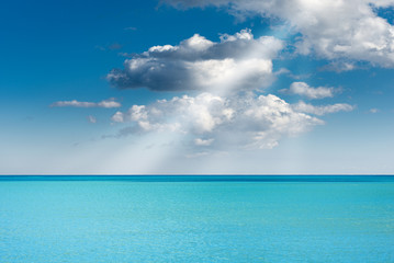 Fototapeta na wymiar Turquoise seascape with blue sky, clouds and sun rays, Mediterranean Sea, Italy, Europe