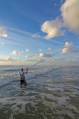Sea fishing,  surf fisherman into the waves cast the line