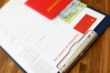 Red passport lie against china application form backgroung cloceup.