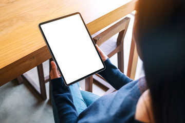 mockup image of a woman holding black tablet pc with blank white screen while sitting in cafe