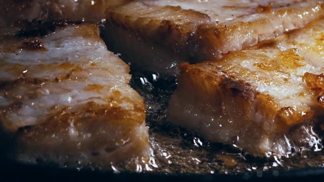 Filets of golden brown fish fry together in sizzling oil, close up.
