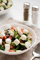 Homemade Shepards salad in a white bowl with cucumbers, parsley and feta, side view. Close-up.