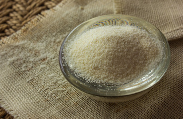Dry semolina durum flour in a pink bowl over white wooden surface, top view. Overhead, from above, flat lay. Close-up.