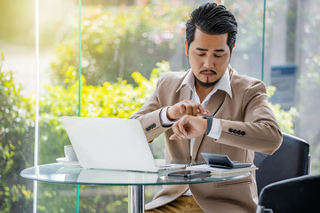business man checking time on smart watch while using laptop