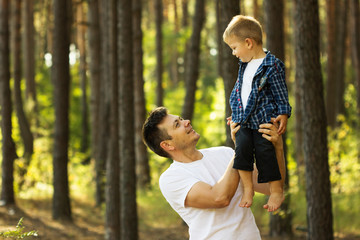 father and son walking along a path in the forest.Happy young father holding up in his arms little baby putting him up. Outdoor portrait. Happiness and harmonyFamily fun outside.