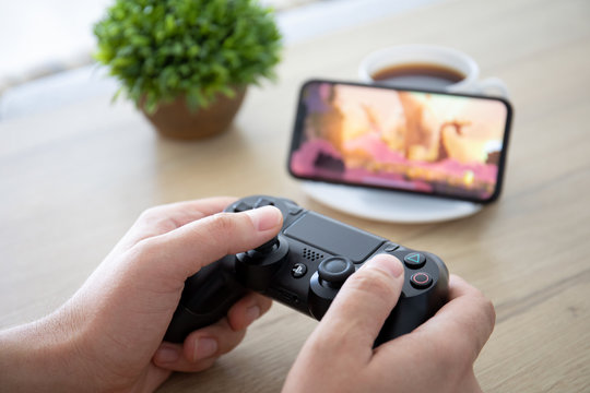 Man holding Dualshock play game Rayman on screen iPhone 11