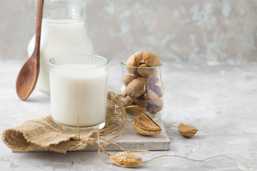 Glass of almond milk with almond nuts on concrete table. Vegan alternative food, non-dairy milk, clean eating concept.