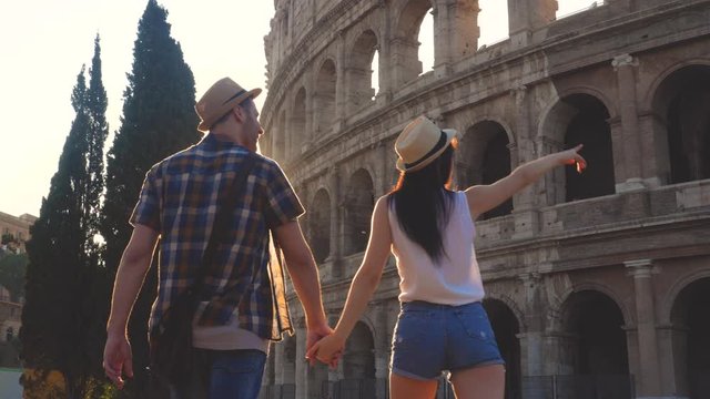 Young couple tourist walking holding hands at Colosseum at sunrise. Rome, Italy.
