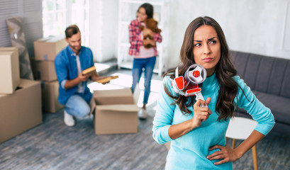 Thoughtful moment. Beautiful woman with long hair is holding a scotch tape in her right hand while...
