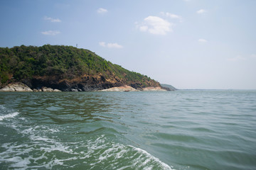 Sea and mountain landscape with trail on water sea surface of fast moving boat in Gokarna, India