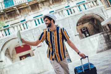 Handsome bearded tourist with backpack is making travel across city.
