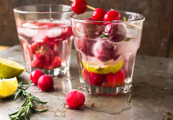 Summer cocktail cherry lemonade. Refreshing water with citron, rosemary  and lemon on grey background. Healthy drink and detox concept. Copy space