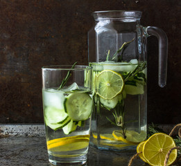 Summer cocktail cucumber lemonade. Refreshing water with cucumber, mint and lemon on grey background. Healthy drink and detox concept. Copy space