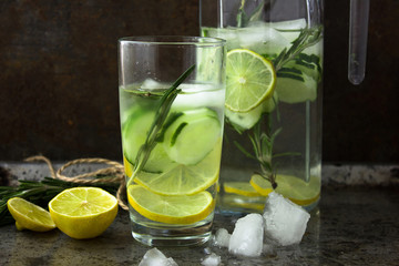 Summer cocktail cucumber lemonade. Refreshing water with cucumber, mint and lemon on grey background. Healthy drink and detox concept. Copy space