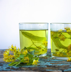 linden tea and linden flowers on white wooden table . Glass cup of healthy medicinal herbal tea. Photo with copy space