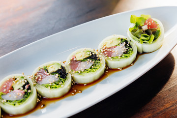 Maguro (Bluefin Tuna), Avocado, Green Oak Maki Sushi Wraped with Sliced Cucumber Topping with sesame and Shoyu sauce.