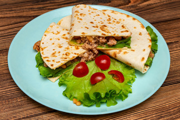 Fototapeta na wymiar fajitos with minced meat vegetables in a corn tortilla on a blue plate dark wooden background. fast food traditional food concept
