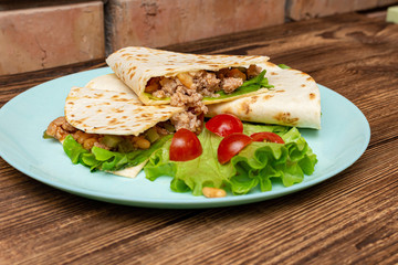 fajitos with minced meat vegetables in a corn tortilla on a blue plate dark wooden background. fast food traditional food concept