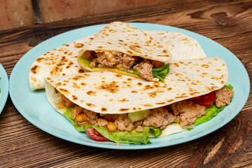 fajitos with minced meat vegetables in a corn tortilla on a blue plate dark wooden background. fast food traditional food concept