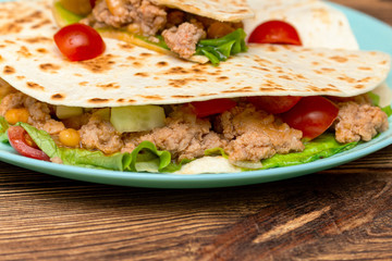 fajitos with minced meat vegetables in a corn tortilla on a blue plate dark wooden background. fast food traditional food concept