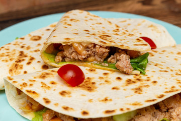 fajitos with minced meat vegetables in a corn tortilla on a blue plate dark wooden background. fast food traditional food concept