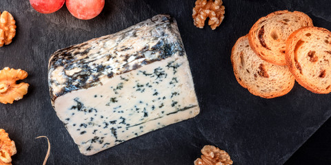A panorama of Gorgonzola cheese, shot from above on a black background with copyspace