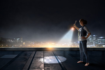 Fototapeta premium Young woman holding a flashlight