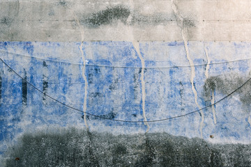 Un mur bleu et gris. La texture d'un vieux mur sale. Des fils pendus sur un vieux mur sale.