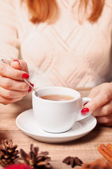 Woman's hand hold cup of tea on the wooden background.