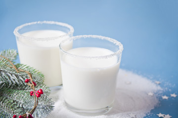 Glasses of milk, pine branch on the blue background