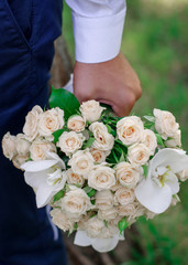 A bouquet of flowers in the male hand. Wedding flowers. The bride's bouquet. The groom carries flowers to his bride.