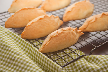 Delicious rustic pastries fresh pies with meat and potato on the metal baking rack