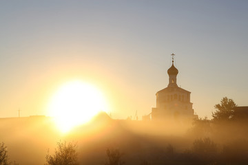 Fototapeta premium Beautiful golden autumn morning foggy sunny field and orthodox church 
