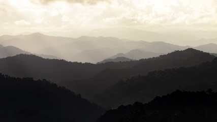 Mountain layers in morning sun ray with winter fog.