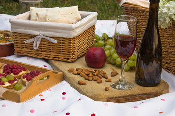 Beautiful delicious picnic food chopped cheese of different types on the board on a pink picnic sheet. Close up