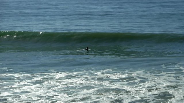 surfer paddling towards the wave but losig the opportunity to ride it. Slow motion extreme long shot