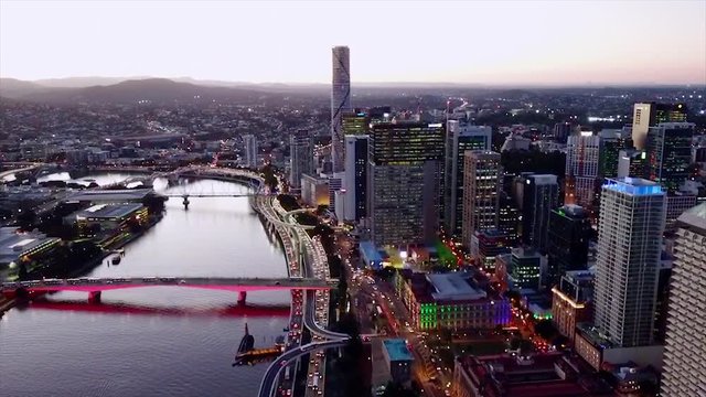 Aerial, drone shot, above cars on a road M3, at brisbane river, bypassing a skyscraper,in downtown, on a clear evening or night, in Brisbane, Queensland, Australia