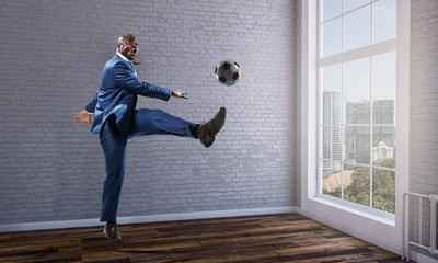 Fototapeta na wymiar Black businessman in a suit playing footbal