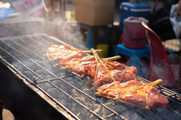 Grilled chicken marinated with curcuma on the charcoal stove ; Thai street food market. 