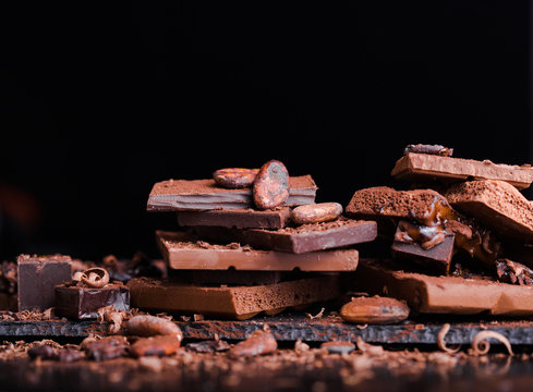Assorted stack Chocolate Candies. Chocolate Sweets. Candy Design over dark brown Background. Various Chocolates. Confectionery