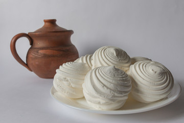 white cream marshmallow lies on a plate next to a jug of milk