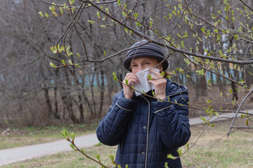 a woman with a pollen allergy covers her face with a white disposable tissue