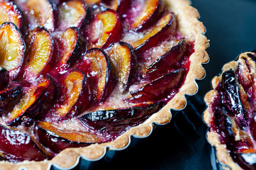 Homemade plum pie on a black background