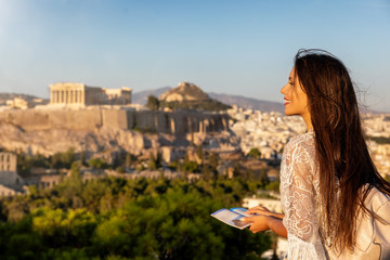 Touristin mit Reiseführer in der Hand schaut auf den Parthenon Tempel der Akropolis von Athen,...
