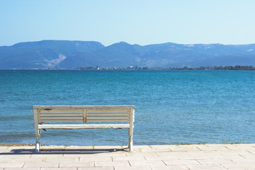 White wooden empty bench in front of the sea