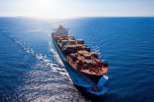 Luftaufnahme ein beladenen Containerschiffes bei voller Fahrt &uuml;ber blauem Meer