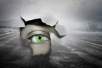 Eye in a hole of torn paper