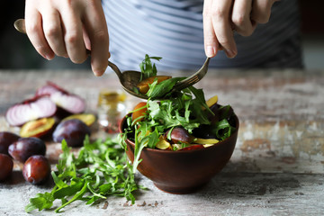 Selective focus. Chef preparing salad with arugula. Healthy salad with arugula and plums.