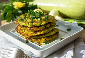 Pan fried zucchini fritters, traditional flat zucchini pancakes with garlic and green parsley