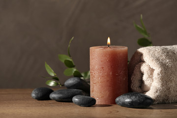 Composition with candle and spa stones on wooden table. Space for text